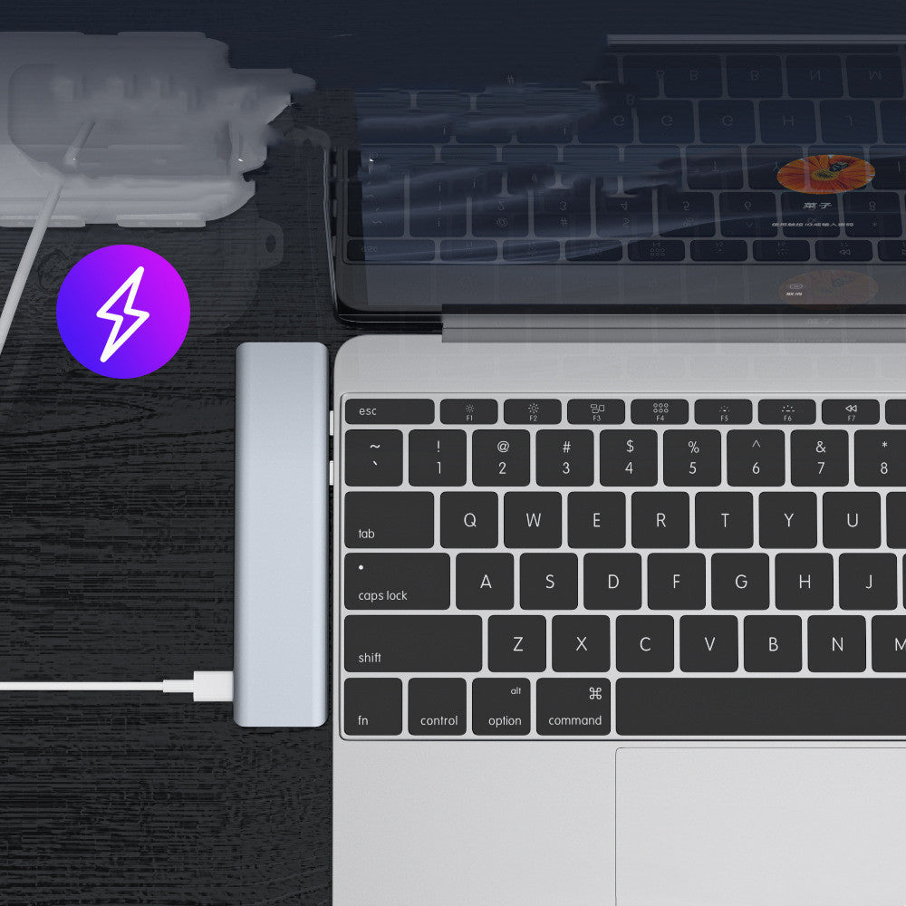 Silver aluminum alloy laptop converter data interface expansion dock connected to a laptop keyboard.