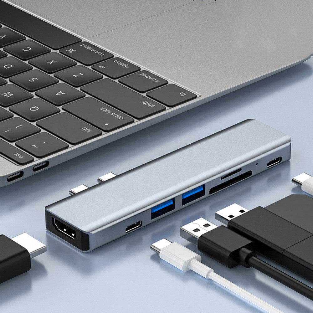 Silver aluminum laptop converter dock with 7-in-1 interface for HDMI, PD, USB, and more.